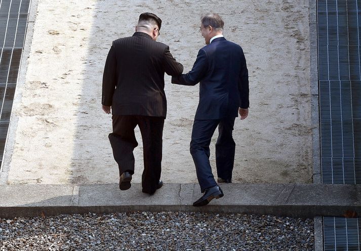 Kim Jong-un og Moon Jae-in stíga yfir landamæri Norður- og Suður-Kóreu.