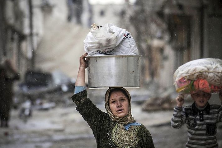 Mæðgur í borginni Aleppo bera eignir sínar á höfðinu eftir að heimili þeirra eyðilagðist í átökum uppreisnarmanna og stjórnarhersins.