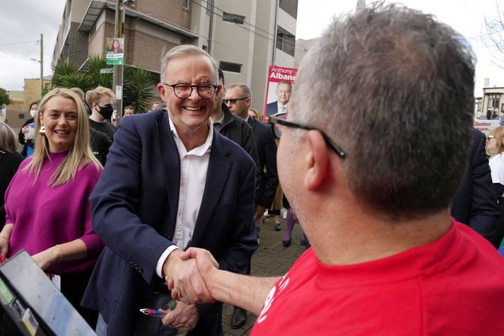 Anthony Albanese, formaður Verkamannaflokksins, tekur í hendina á kjósanda áður en hann kaus sjálfur í dag.