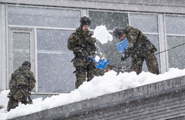 Hermenn losa snjó af þaki grunnskóla í Bæjaralandi.