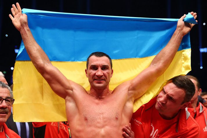 Wladimir Klitschko fagnar sigri í hnefaleikhringnum með úkraínska fánann.