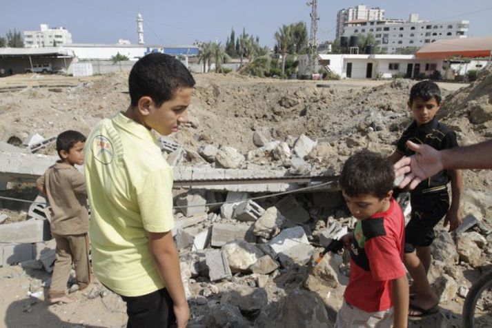 Palestínsk börn standa við svæðið þar sem loftárásirnar áttu sér stað fyrr í dag.