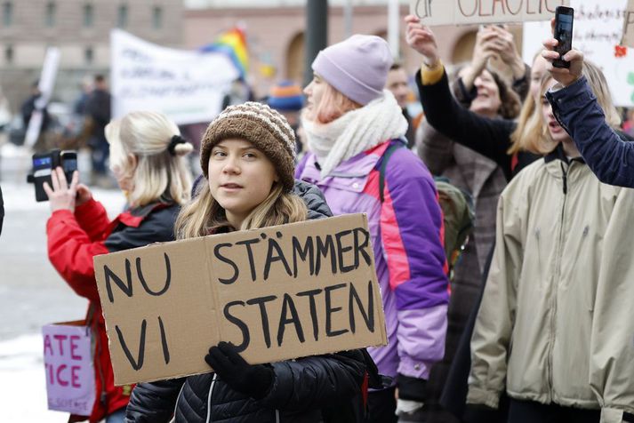 Loftslagsaðgerðasinninn Greta Thunberg heldur á spjaldi sem á stendur „Nú stefnum við ríkinu“ á mótmælum Aurora í Stokkhólmi í nóvember.