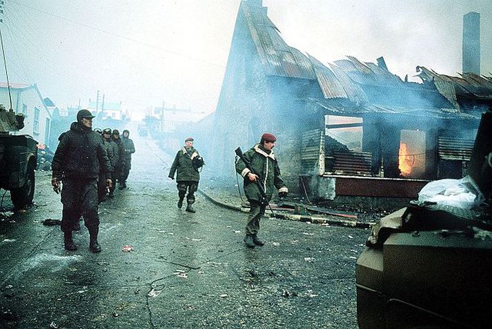 Í Port Stanley Argentínskir stríðsfangar í gæzlu brezkra hermanna ganga hjá brennandi byggingu í Port Stanley á lokadögum Falklandseyjastríðsins. fréttablaðið/ap