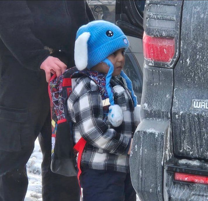 Fulltrúi ICE heldur í skólatösku Liam Ramos í innkeyrslunni við heimili drengsins.