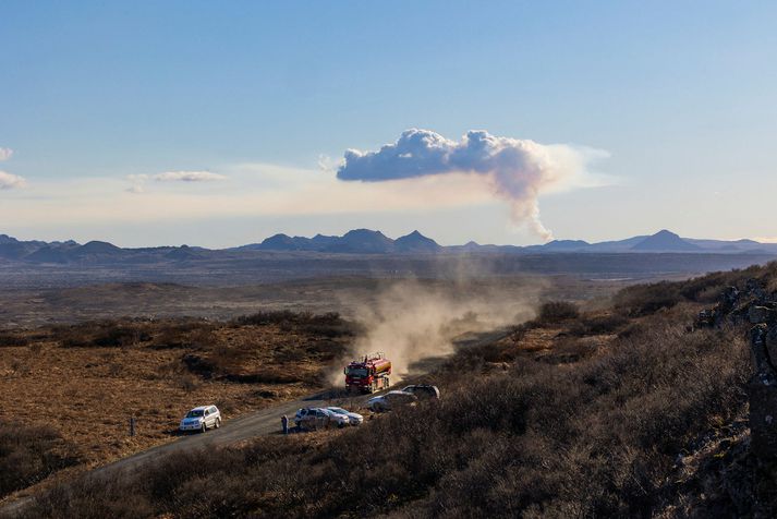 Frá störfum slökkviliðs á þriðjudaginn. Í bakgrunni sést reykurinn úr eldgosinu í Fagradalsfjalli.