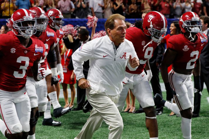 Nick Saban hleypur með sínum strákum inn á völlinn.