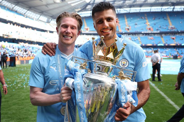 Rodri stillir sér upp með Englandsbikarinn og við hlið Kevin De Bruyne. Margir telja að þessir tveir séu aðalástæðan fyrir ótrúlegu gengi City liðsins undanfarin fjögur tímabil.