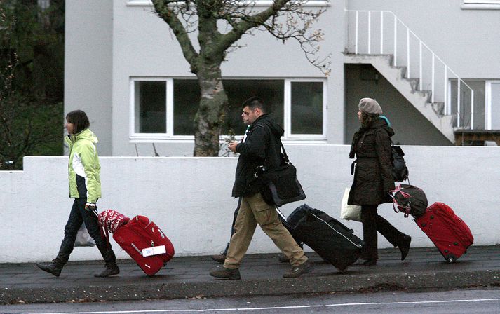 Erlendir ferðamenn á gangi um Flókagötu með ferðatöskur í skammdeginu