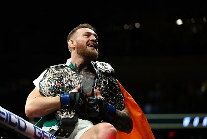 Conor McGregor fagnar með bæði beltin.