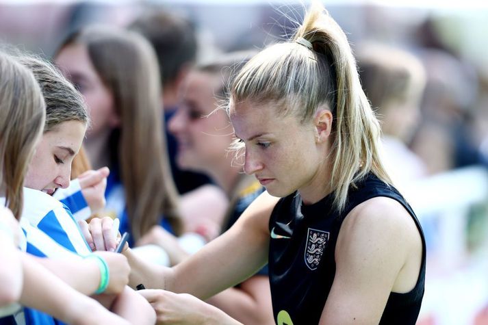 Fyrirliðinn Leah Williamson með pennann á lofti að gefa ungum aðdáendum eiginhandaráritun.
