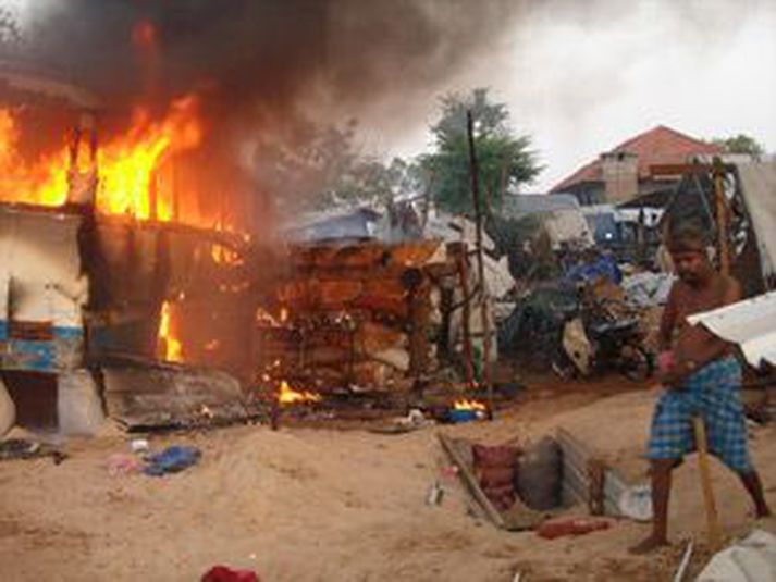 Eldur logar í byggingu eftir stórskotaliðsárás stjórnarhersins í fyrradag.