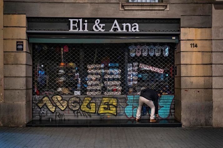 Búðareigandi lokar snemma í Barcelona á Spáni. Faraldurinn og sóttvarnaaðgerðir hafa lagst þungt á fyrirtæki og heimili víða um heim. Mótvægisaðgerðir sem var gripið til í mörgum löndum eru nú að renna sitt skeið þrátt fyrir að faraldurinn sé víða í mikilli sókn.