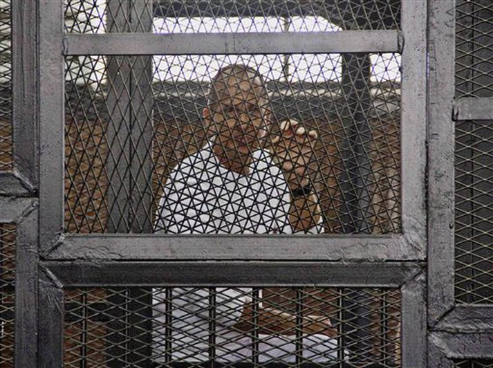 Peter Greste, verðlaunaður fréttamaður Al-Jazeera's, í rammgerðri vitnastúku herdómstóls í Egyptalandi.