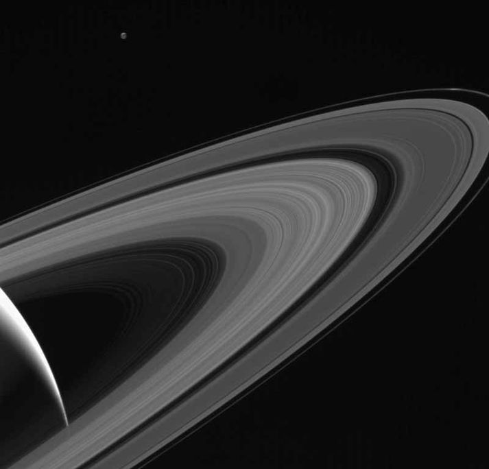 Uppruni hringja Satúrnusar eru enn óþekktir. Fyrir ofan þá sést tunglið Tethys á mynd Cassini frá 13. maí.