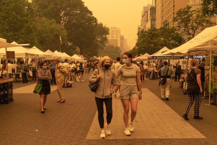 Grímuklæddar stúlkur á götum New York þar sem loftgæði eru slæm vegna mikilla gróðurelda norðan landamæranna í Kanada.