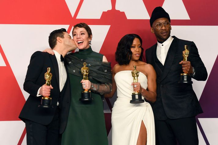 Leikarar stilla sér upp með Óskarsverðlaunin sín, Rami Malek laumar kossi á kinn Oliviu Colman á meðan Regina King og Mahershala Ali líta undan.