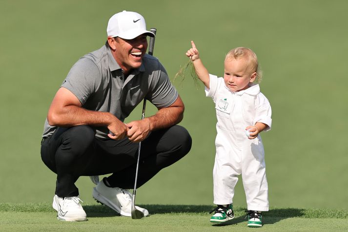  Brooks Koepka fylgist kátur með barninu sínu leika sér á flötinni á einni af par þrjú holunum á Augusta golfvellinum.