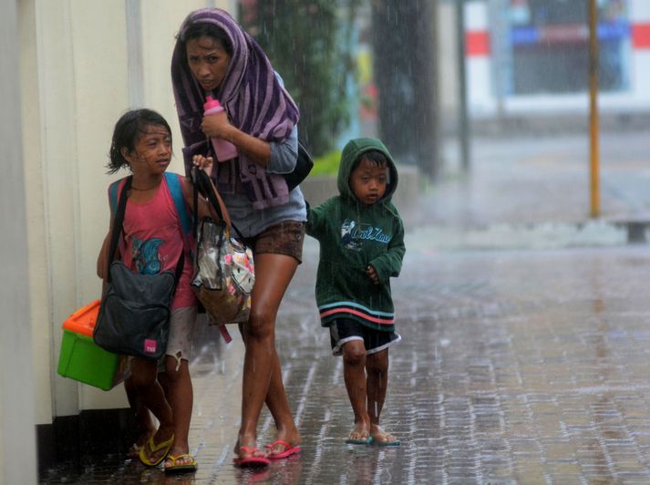 Móðir heldur ásamt tveimur börnum sínum í bráðabirgðaskýli í borginni Cebu, þar sem úrhellisrigning og hvassviðri hefur dunið á íbúum.