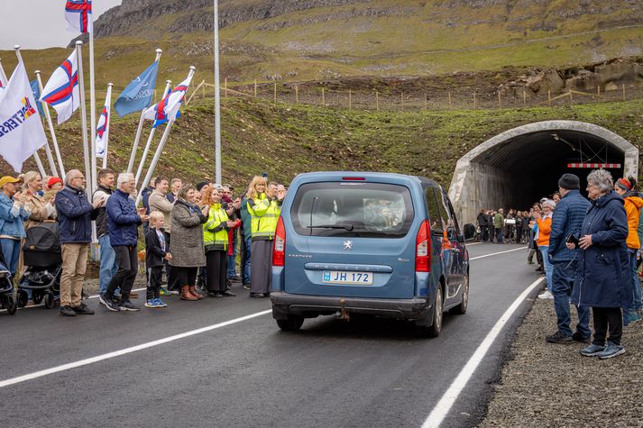 Elsti íbúi Fámjin ekur fyrsta bílnum í gegn við fögnuð viðstaddra.
