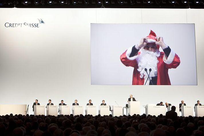 Aðgerðasinni í hópi hluthafa Credit Suisse uppáklæddur sem jólasveinninn birtist á skjá að baki æðstu stjórnendum bankans í mótmælum gegn ofurbónusum á aðalfundi bankans 30. apríl síðastliðinn. Fréttablaðið/AP