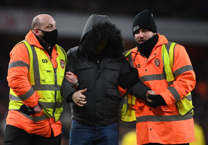 Gæslumenn vísa stuðningsmanni sem ruddist inn á völlin í leik Arsenal og Liverpool í gær af velli.