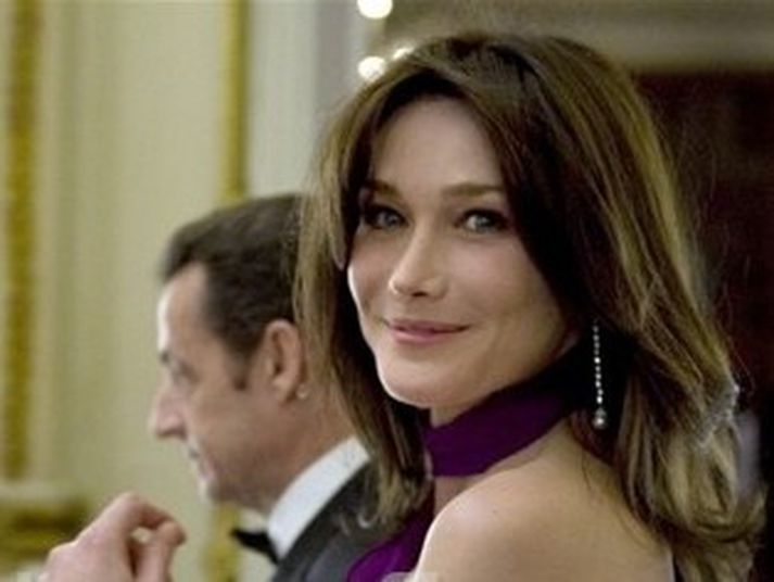 Carla Bruni og Nicholas Sarkozy í bakgrunni.