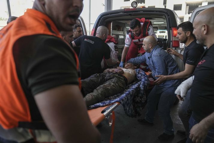 Sjúkraflutningamenn bera særðan Palestínumann í flóttamannabúðum í Jenín á Vesturbakkanum í dag.