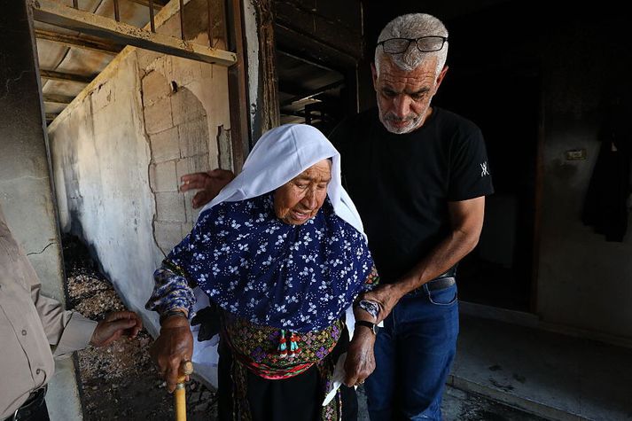 Palestínsk kona snýr hér til baka á heimili sitt eftir eftir að ísraelskt landtökufólk hafði kveikt í því. Myndin var tekin í gær á Vesturbakkanum sunnanverðum, nærri Hebron.