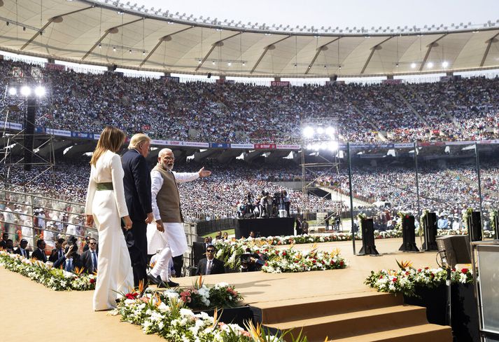 Modi leiðir Trump-hjónin út á sviðið á Sardar Patel-leikvanginum í Ahmedabad í dag.