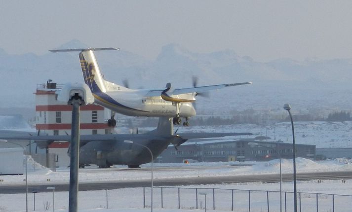 Dash 8-vél Flugfélags Íslands svífur til lendingar á hinni umdeildu flugbraut á sjöunda tímanum í kvöld. Hercules-vél kanadíska hersins er við gamla flugturninn.