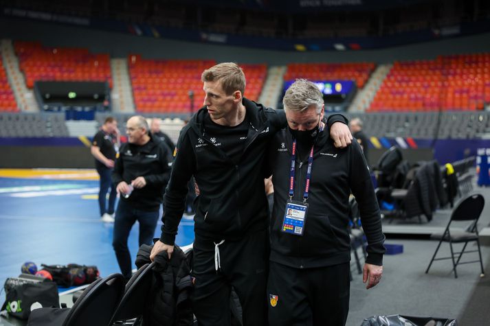 Ólafur Guðmundsson studdur af velli af starfsmanni HSÍ, eftir að hafa meiðst gegn Suður-Kóreu.