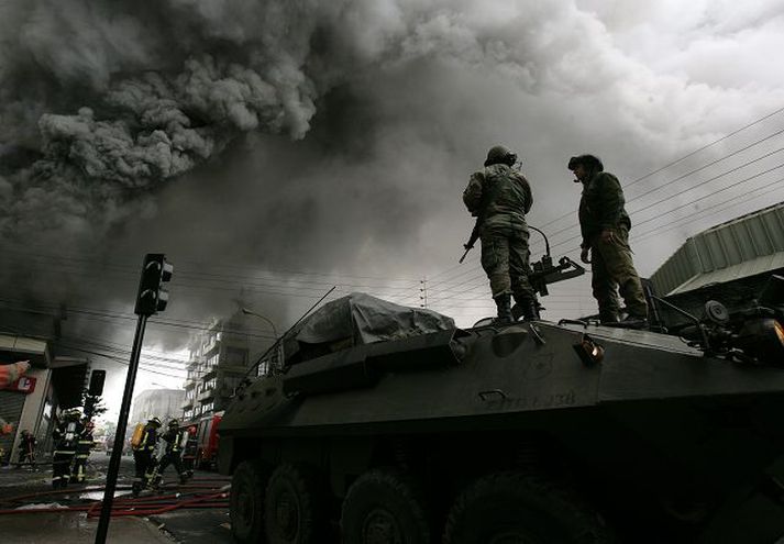 Eldar loga Þykkur reykur barst frá matvörubúð í Concepcion í Chile í gær, þar sem hermenn stóðu vörð.nordicphotos/AFP