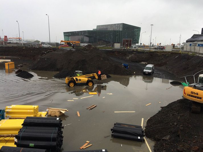 Vinnumaður fluttur á milli staða yfir vatnið í dag með gröfu.