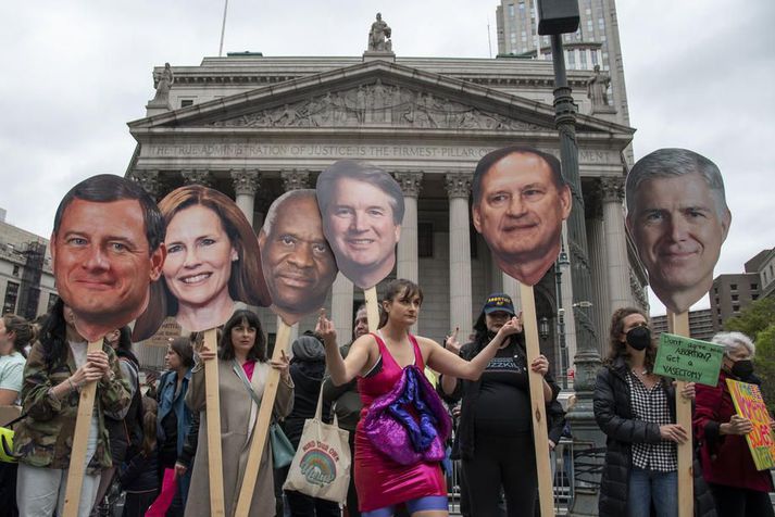 Mótmælendur í New York haldi á lofti spjöldum með andlitum íhaldsmannanna sex við Hæstarétt Bandaríkjanna. Fimm þeirra stóðu að meirihlutaálitinu, þau Amy Coney Barrett, Clarence Thomas, Brett Kavanaugh, Samuel Alito og Neil Gorsuch. John Roberts, forseti Hæstaréttar, (lengst til vinstri), er talinn vilja ganga skemur en félagar sínir í að takmarka þungunarrof.