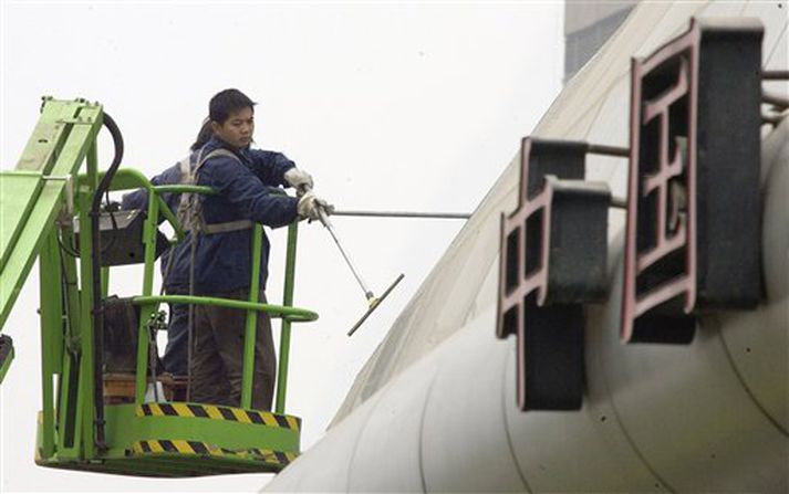 Borgarstarfsmenn þrífa sand af byggingu í Peking í dag.