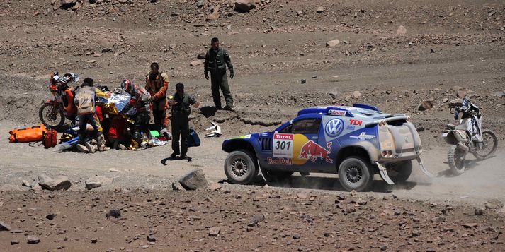 Carlos Sainz ekur framhjá slysstaðnum í gær, þar sem hugað er að landa hans Cristobal Guererro.