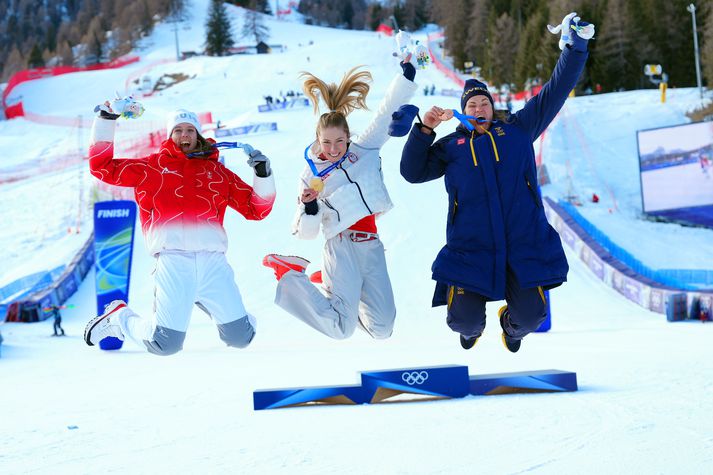 Ólympíumeistarinn Mikaela Shiffrin hoppar hér á verðlaunapallinum með verðlaun sín ásamt silfurverðlaunahafanum Camille Rast og svissneska bronsverðlaunahafanum Anna Swenn Larsson sem er lengst til hægri.