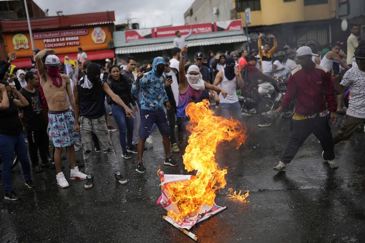 Veggspjöld af Maduro í ljósum logum í Caracas í dag. 