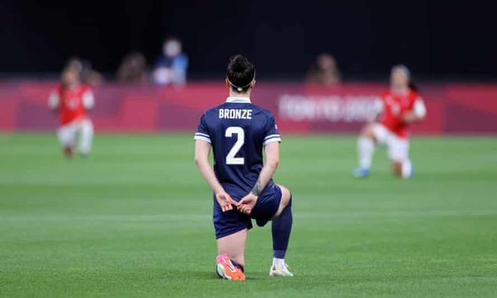 Lucy Bronze fyrir leik Bretlands og Síle. Einnig má sjá tvo leikmenn Síle krjúpa á myndinni.