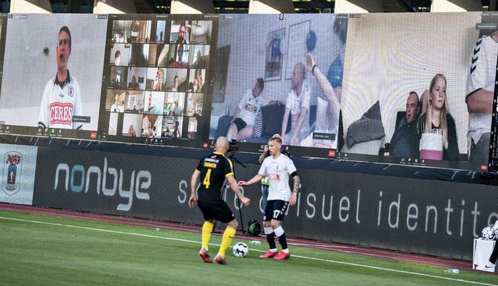 Jón Dagur Þorsteinsson með boltann í leik AGF og Randers í gær en fyrir aftan hann má sjá sýndaráhorfendurnar sem studdu liðið sitt í gegnum Zoom fjarfundabúnaðinn.