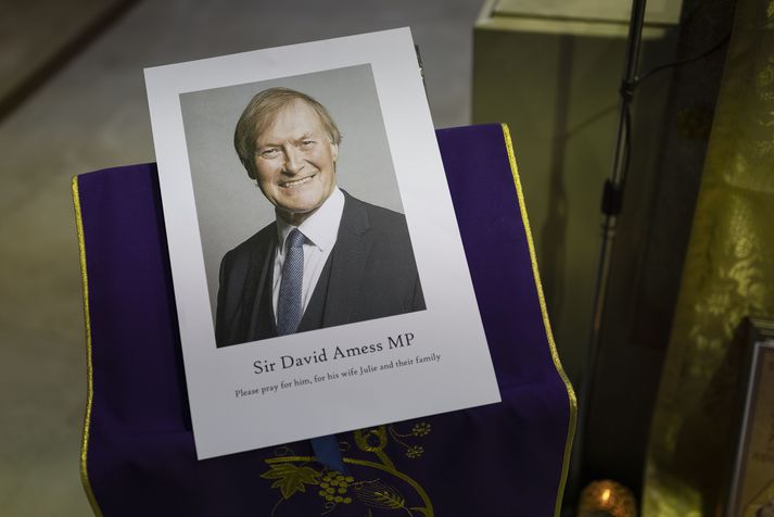 Mynd af af minningarathöfn Sir David Amess. Undir nafni þingmannsins er texti sem á stendur: „Biðjið fyrir honum, konu hans og fjölskyldu þeirra.“