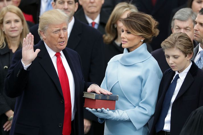 Donald Trump þegar hann sór embættiseið í gær. Melania, kona hans, heldur á biblíum Lincolns annars vegar og móður Trumps hins vegar. Með þeim stendur sonur þeirra, Barron.