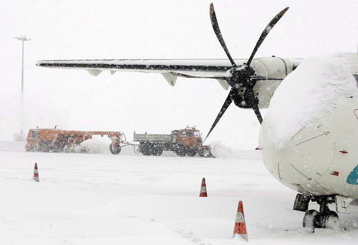 Snjóplógur ryður flugbraut í gærmorgun. Loka þurfti flugvellinum vegna snjóþungans.