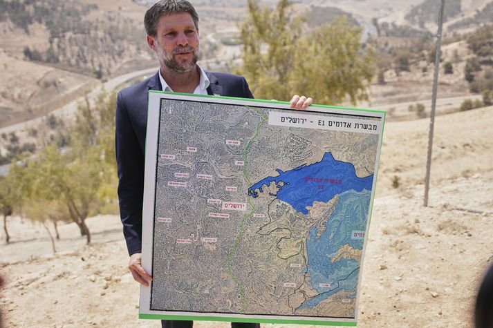 Bezalel Smotrich heldur á korti sem sýnir fyrirhuguðu landtökubyggðina á Vesturbakkanum þegar hann tilkynnti um að hann ætlaði að gefa henni grænt ljós í dag.