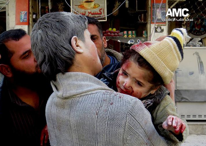 Maður í Aleppo ber sært barn burt eftir sprengingu á mánudag.