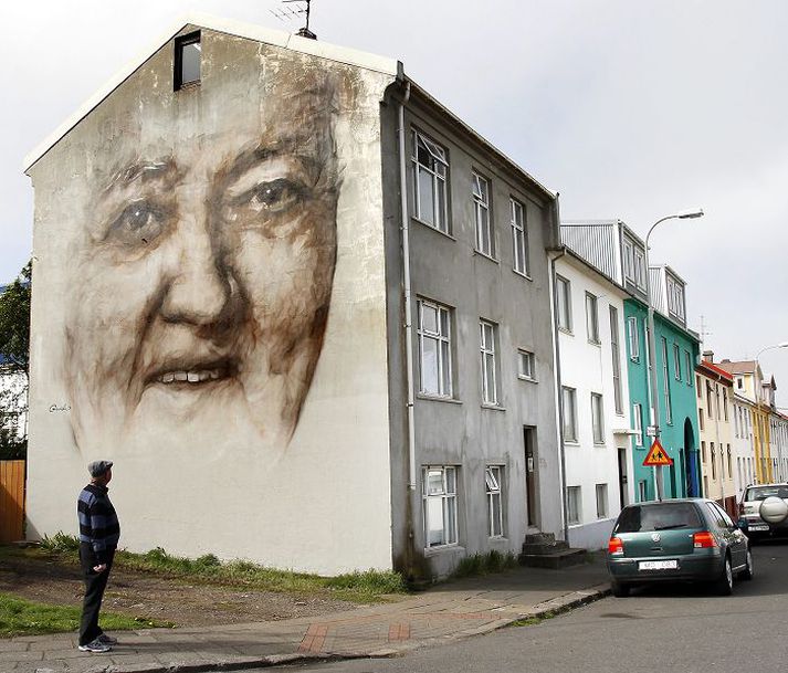 Maðurinn á myndinni horfir glaðlegum augum á vegfarendur í Vesturbænum. Myndin er eftir ástralska listamanninn Guido Van Helten.