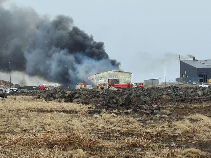 Búið er að slökkva eldinn en Brunavarnir Suðurnesja eru enn með mannskap við brunavettvang til að vakta timburhaug þar sem enn gæti logað í glæðum.