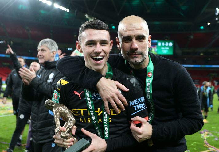 Phil Foden og Pep Guardiola eftir úrslitaleik enska deildabikarsins þar sem Manchester City vann Aston Villa, 2-1. Foden var valinn maður leiksins.