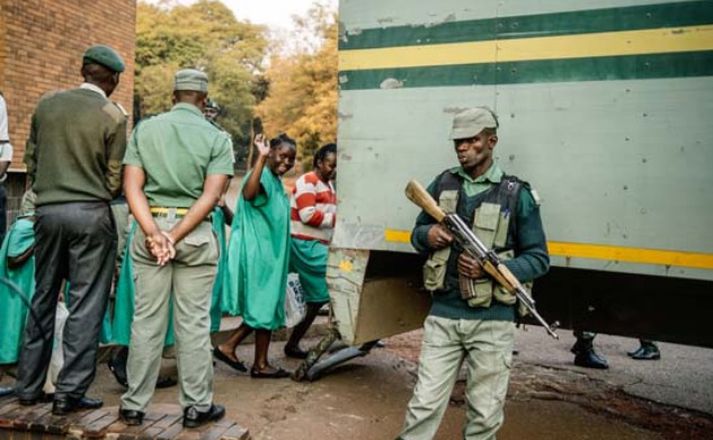 Stuðningsmaður MDC sýnir merki flokksins á meðan henni er fylgt inn í fangabíl. 27 meðlimir MDC hafa verið handteknir vegna átaka síðasta miðvikudags í Harare. Stjórnvöld eru sögð ganga fram með mikilli hörku.